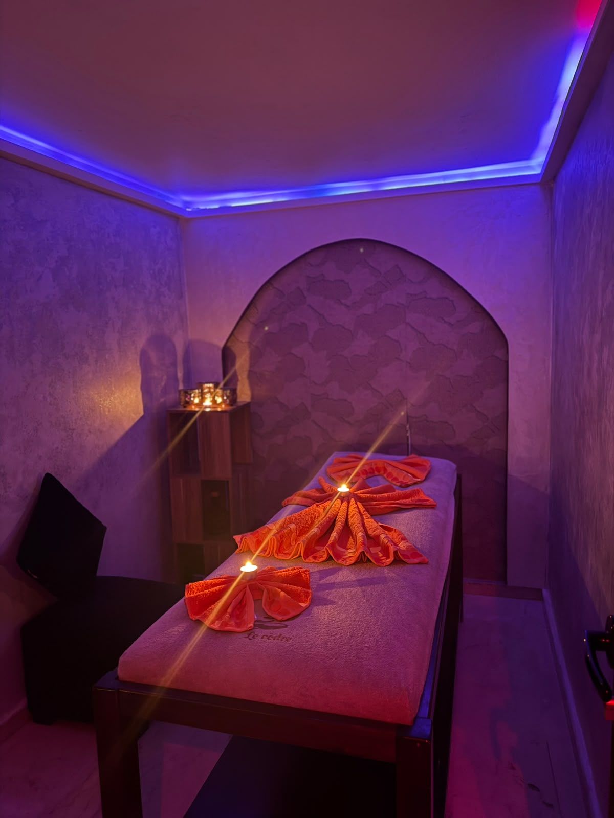 Cabine de soin à l’arche orientale de Le Cèdre Lounge Spa, serviettes orangées pliées en éventail et bougies