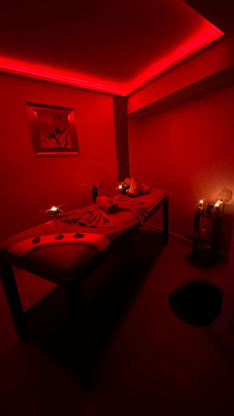 Cabine de massage de Le Cèdre Lounge Spa sous lumière rouge, table habillée et bougies