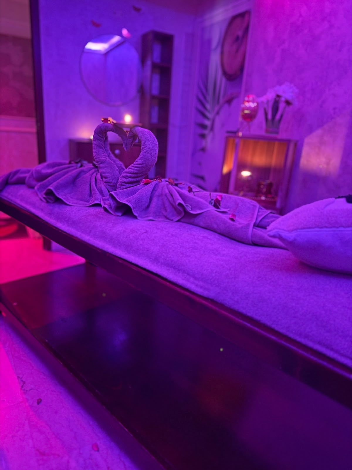 Serviettes pliées en forme de cygnes formant un cœur sur une table de massage de Le Cèdre Lounge Spa